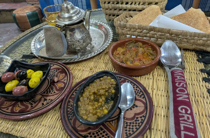 Assortiment de salades marocaines, olives, pain et théière en argent sur un plateau