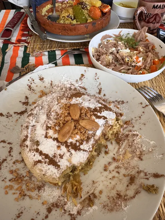 Pastilla saupoudrée de sucre glace et de cannelle, décorée d'amandes entières