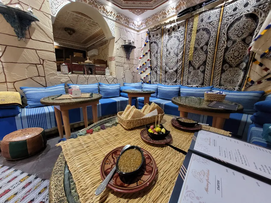 Notre salle : banquettes bleues à rayures, tables basses en cuivre et tentures murales