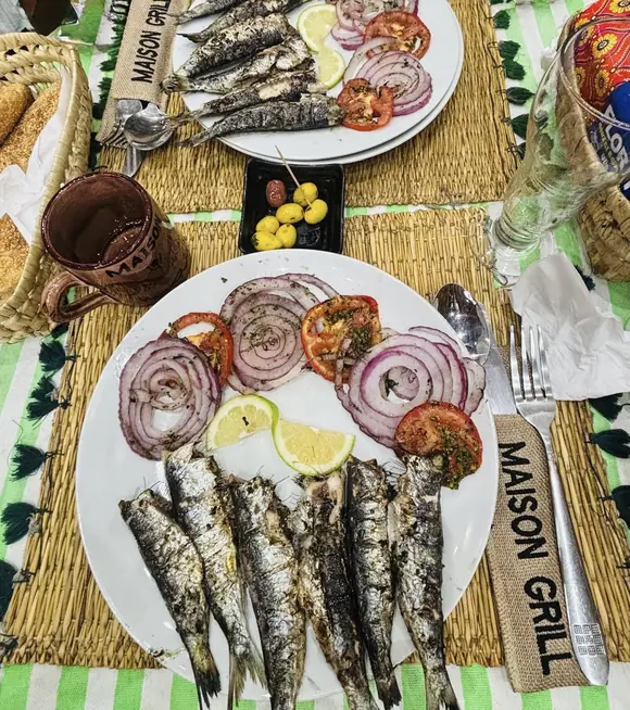 Deux assiettes de sardines grillées, avec oignon rouge, tomate et citron